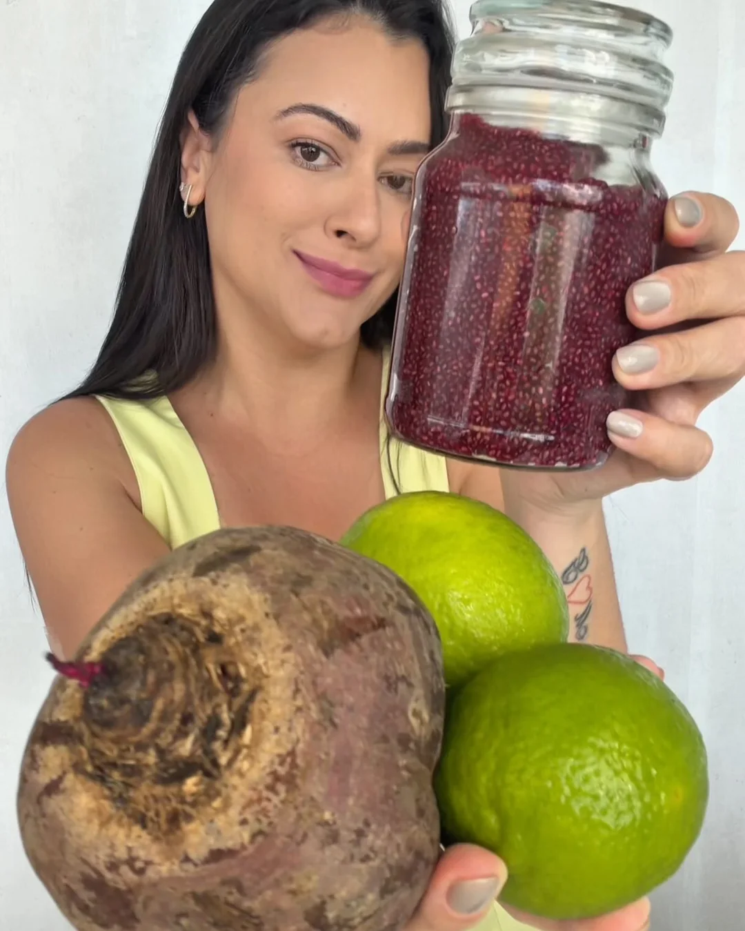 Lanna na cozinha, segurando uma jarra de bebida vermelha e limões