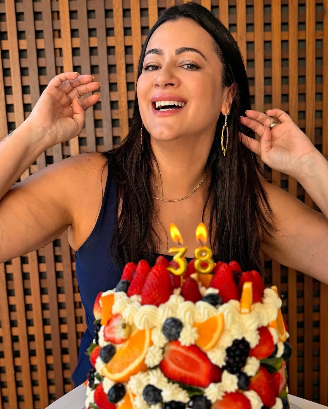 Lanna sorrindo diante de um bolo de aniversário feito com frutas